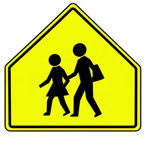 A school zone sign is five-sided and has a fluorescent yellow/green background with black symbols